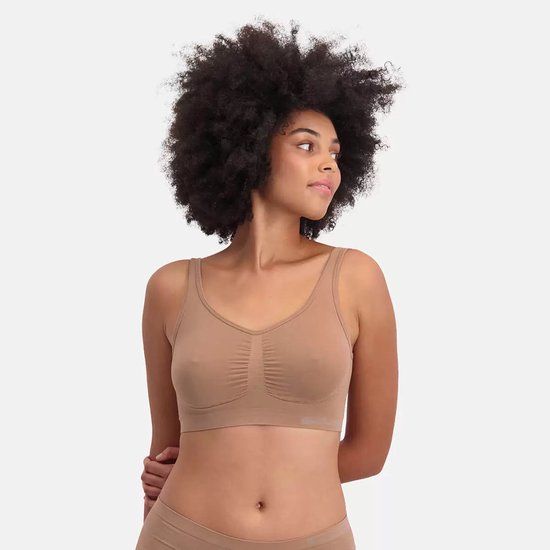 Een vrouw met een grote afro, draagt een bruine naadloze bh zonder beugel. Ze kijkt weg van de camera.