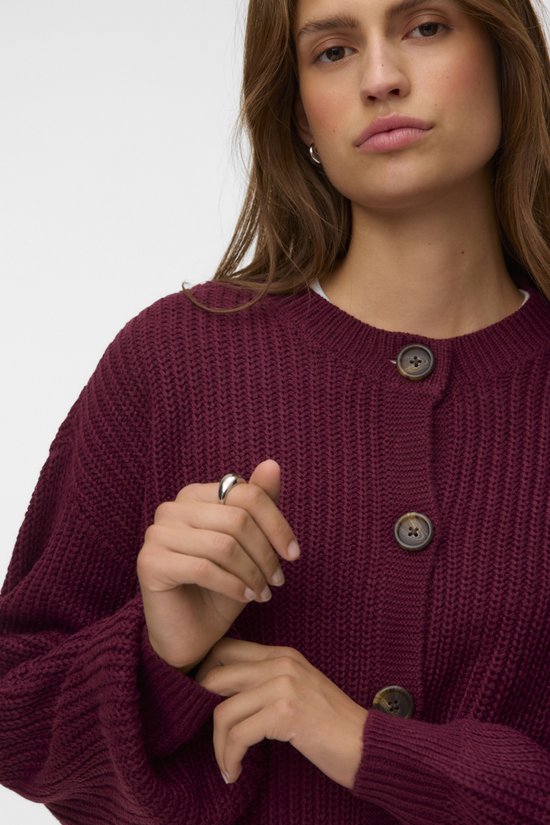 Close-up van een bordeauxrode gebreide cardigan met knopen, model met ring.