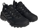 Een paar zwarte dames wandelschoenen met zwarte Adidas-strepen, veters en een robuuste zool.