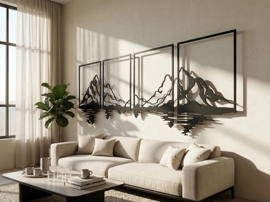 Zwarte metalen wanddecoratie met berglandschap en reflectie, in vierkante lijsten, boven een bank in een woonkamer.
