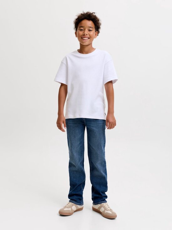 Jongen in witte t-shirt en blauwe jeans met bruine sneakers.