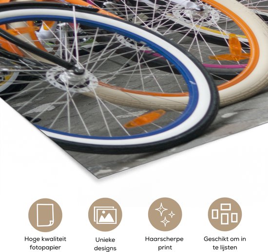 Une rangée de vélos colorés avec des jantes orange, bleues, blanches, roses et jaunes.