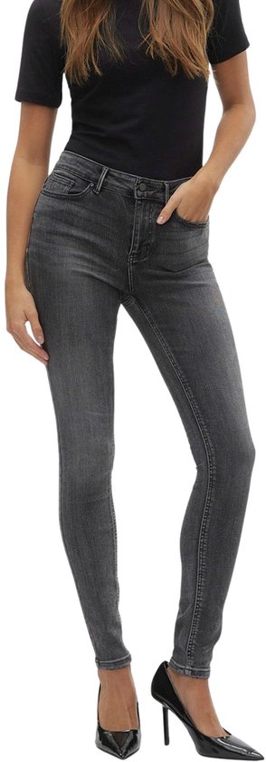 Model draagt een grijze skinny jeans met middelhoge taille en een zwart T-shirt.