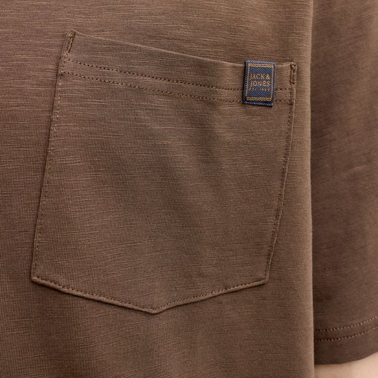 Close-up van het borstzakje van een bruin T-shirt met een Jack & Jones label.