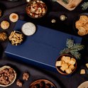 Kerstpakket met kaas, worst, noten, crackers, dip en snacks, met de tekst 'Zuivelhoeve' op de doos.