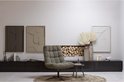 Zwart dressoir met een grijze fauteuil ervoor, decoratie en een spiegel.