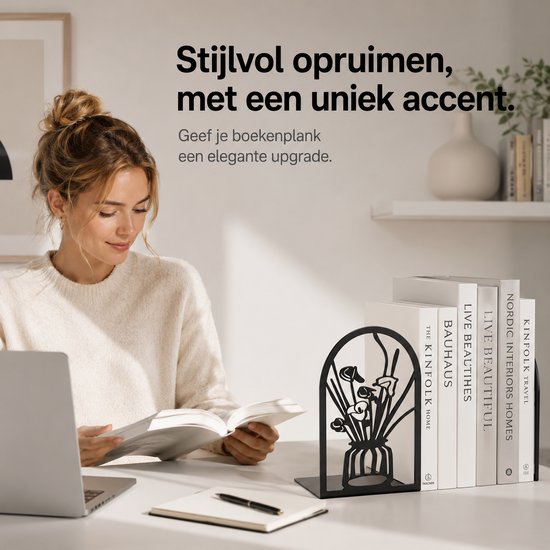 Zwarte metalen boekensteun met bloemen in een vaas, die boeken rechtop houdt. Een vrouw leest aan een bureau met een laptop.