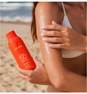 Een vrouw met een witte bikini brengt Lancaster Sun Beauty Body Milk SPF50 aan op haar arm.