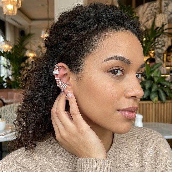 Model met meerdere zilverkleurige oorclips, waaronder een op de oorrand versierd met strass-steentjes.