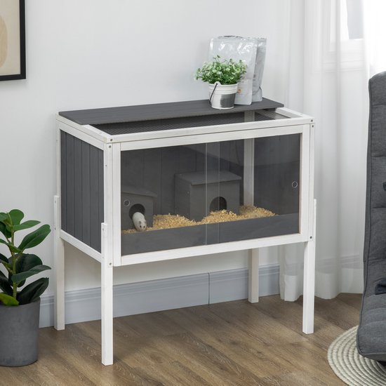 Grijze en witte hamsterkooi met glazen deuren, een hamstertje en een opbergrek met plant.