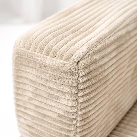 Beige corduroy stof met fijne ribbels op een hoek van een bank.