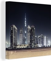 Canvas Schilderij De Burj Khalifa verlicht met andere wolkenkrabbers de lucht boven Dubai - 90x90 cm - Wanddecoratie