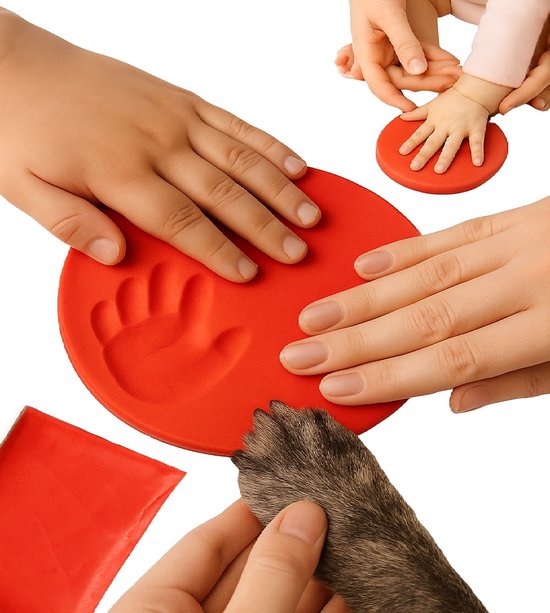 Une main et une patte font des empreintes dans de l'argile rouge. Main de bébé dans un petit moule en argile rouge.