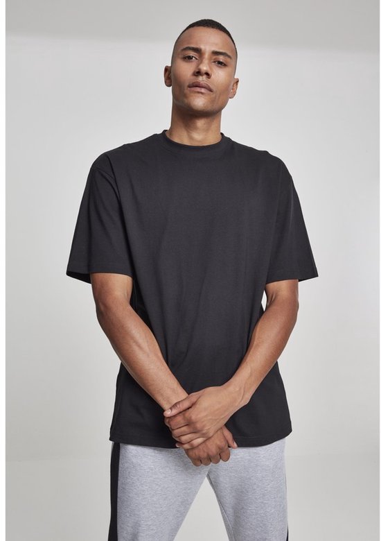 Man met korte haren, draagt een zwart T-shirt en grijze joggingbroek met zijstreep.