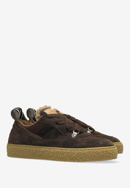 Gedetailleerde opname van een donkerbruine suède sneaker met bontvoering en crèpezool.