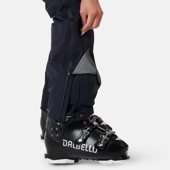 Dichtbij de onderkant van een donkerblauwe skibroek, model opent een rits.