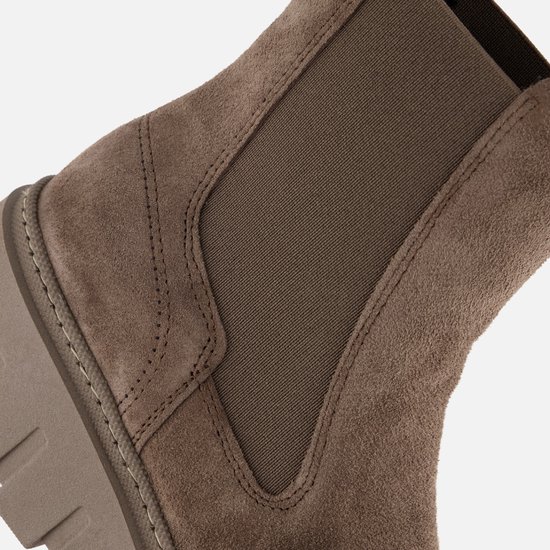 Detail van beige suède Chelsea laars met elastische zijkanten en stiksels.