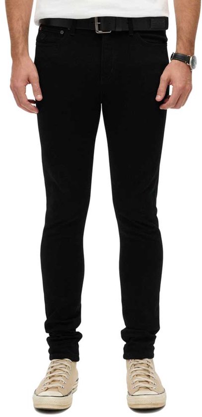 Homme portant un jean skinny noir Superdry, vu de face, avec une ceinture et une montre.