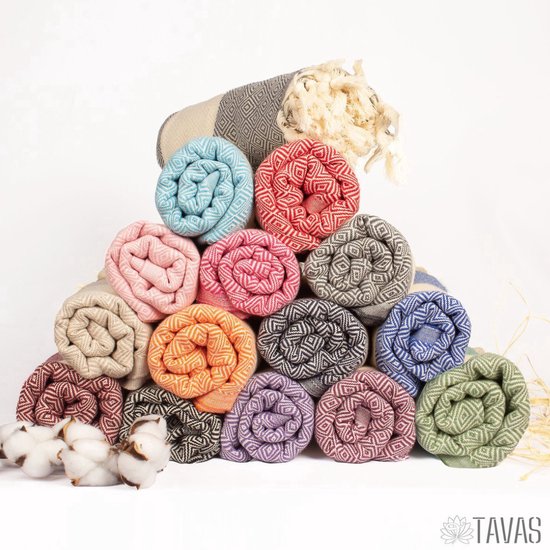 Gestapelde hamamdoeken in diverse pastelkleuren, gerold met ruitpatroon en franjes.