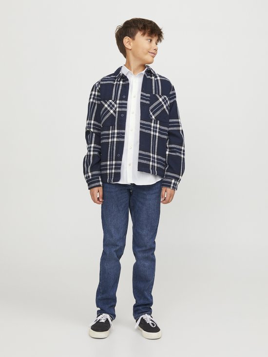 Garçon en chemise blanche, chemisier à carreaux tricoté et jean.