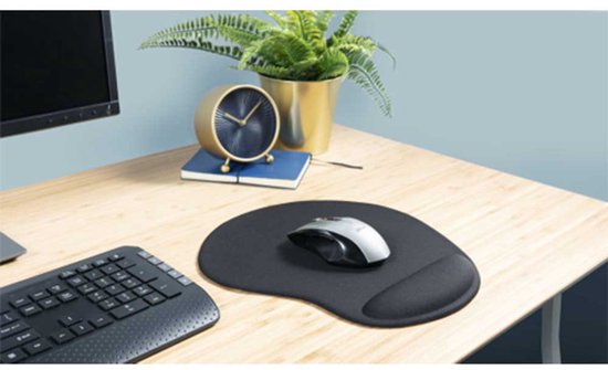 Tapis de souris noir avec repose-poignet, avec une souris dessus, sur un bureau en bois à côté d'un clavier et d'une plante.