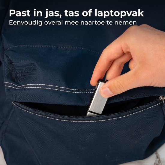 Hand die een zilverkleurige usb-stick in een donkerblauwe rugzak steekt.