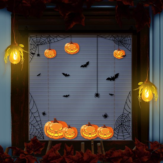 Raamdecoratie met spinnenwebben, vleermuizen en pompoenen voor Halloween.