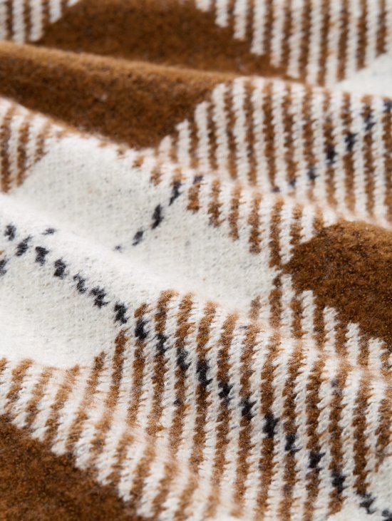 Detail van een bruin en wit geruit gebreid vest.