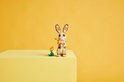 Lapin LEGO avec carotte et fleur, sur bloc jaune.
