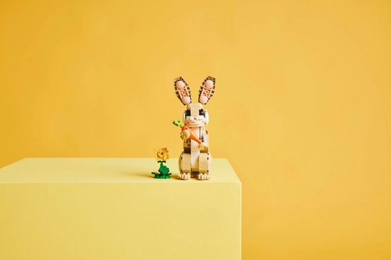 Lapin LEGO avec carotte et fleur, sur bloc jaune.