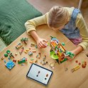 Een meisje bouwt met LEGO Friends aan een boomhut, met een tablet.