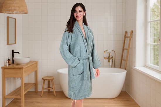 Jeune femme dans une salle de bain, portant une robe de chambre bleu clair, douce, avec ceinture et poches plaquées.