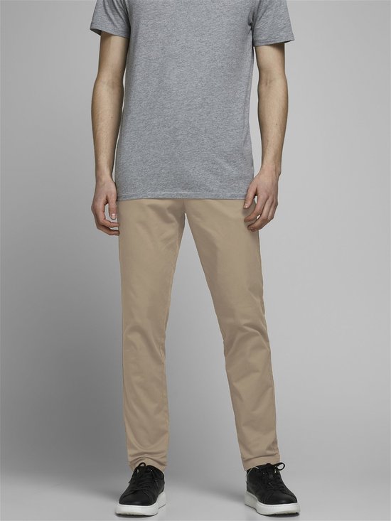 Model in een grijs T-shirt en beige chino. De voorkant van de broek is zichtbaar.
