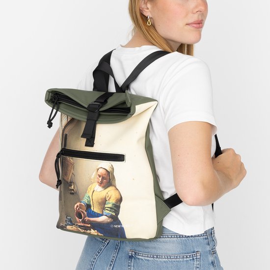 Vrouw met rugzak met print van Vermeer's Melkmeisje op haar rug.