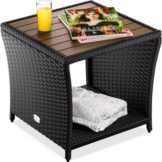 Zwarte vierkante bijzettafel met houten tafelblad, met tijdschriften en glas sap.