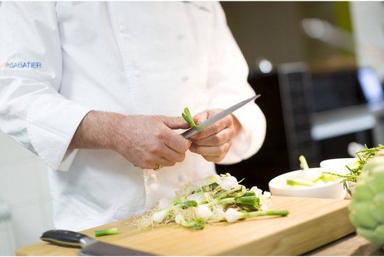 Chef snijdt groen van een bosuitje met een mes.
