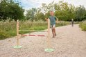 Jongen rent naar een hordenparcours met twee staanders en twee balken: groen-hout en rood-wit geblokt.