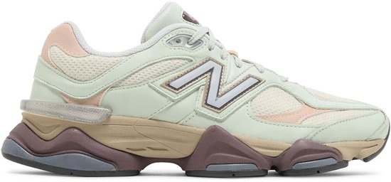 Lichtgroene New Balance 9060 sneaker met roze en beige accenten, zilverkleurig N-logo en dikke, gelaagde zool.