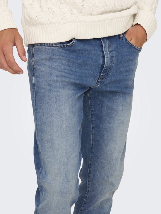 Detail van een man in blauwe jeans, met een hand in de zak.