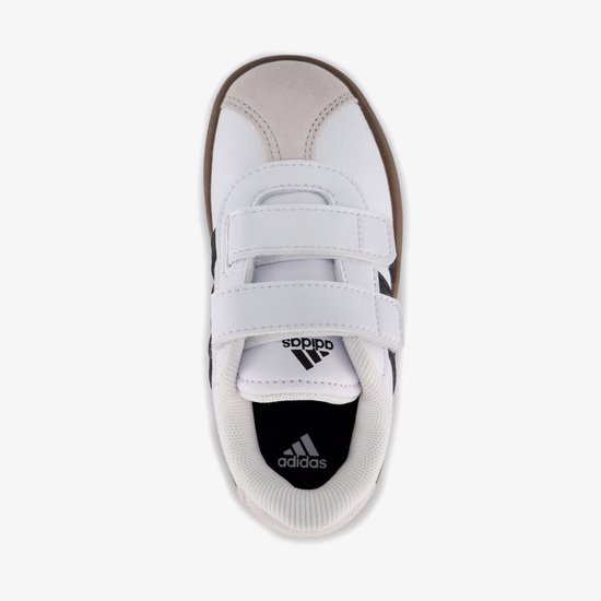Bovenkant van een witte sneaker met klittenbandsluiting, zwarte strepen en beige accenten.