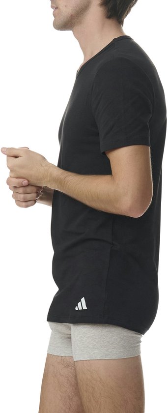 Man in zwart Adidas T-shirt en grijze boxershort, van de zijkant gezien.