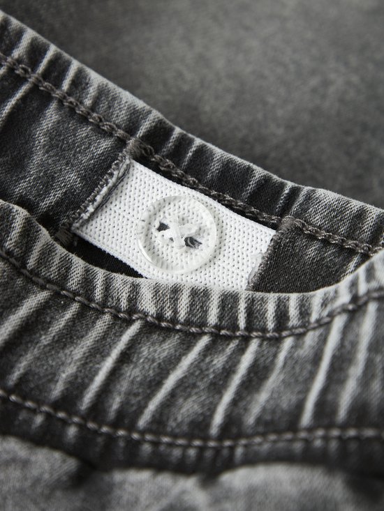 Verstelbare tailleband van de grijze jeans met drukknoopsluiting.
