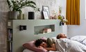 Zwarte Harman Kardon speaker boven een bed met slapend koppel.