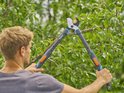 Man houdt de GARDENA Takkenschaar TeleCut Pro S met oranje knoppen vast.
