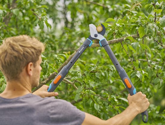 Man houdt de GARDENA Takkenschaar TeleCut Pro S met oranje knoppen vast.