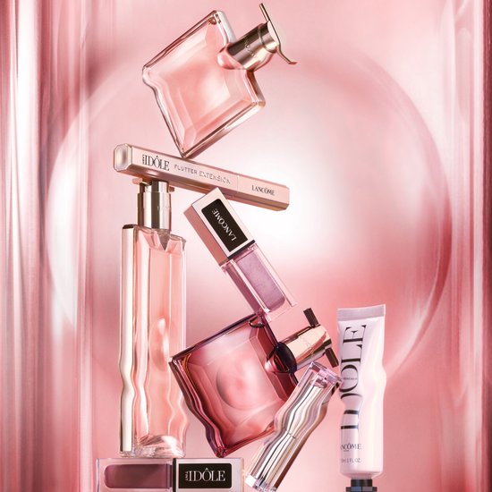 Stapel Lancôme Idôle cosmetica en parfumflessen met roze accenten en achtergrond.