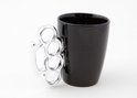 Tasse noire avec une poignée chromée en forme de poing américain.