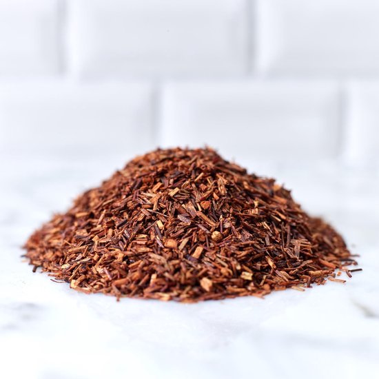 Een hoopje fijngesneden rooibos thee met een bruinrode kleur op een marmeren ondergrond.