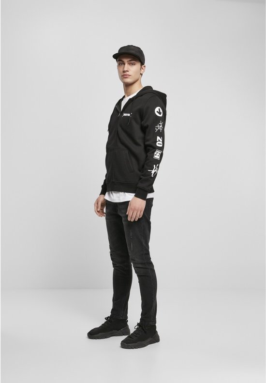 Man met pet, draagt een zwarte hoodie met ritssluiting met 'Linkin Park' logo en witte grafische prints op de mouw.