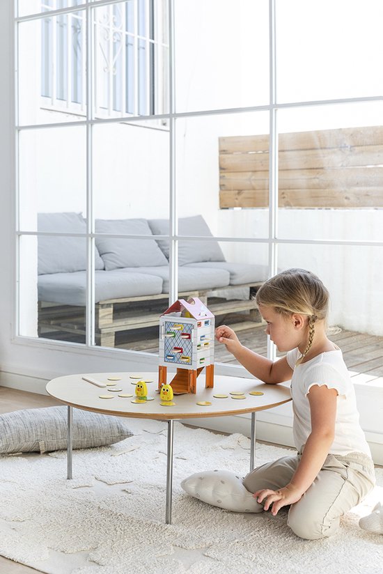 Meisje speelt met Happy Chickens spel aan een ronde tafel.